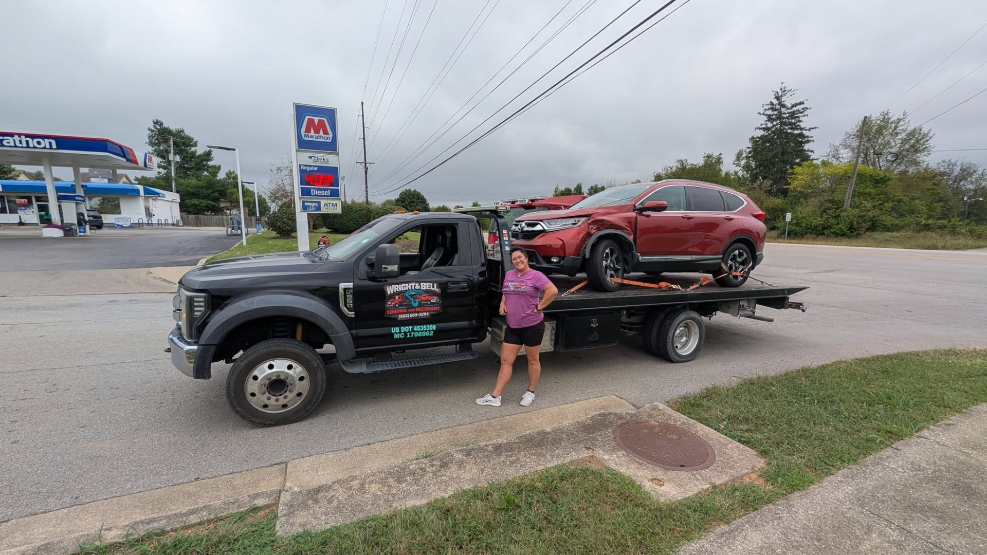 The Wright & Bell tow truck stopped at an intersection with a car on the flatbed