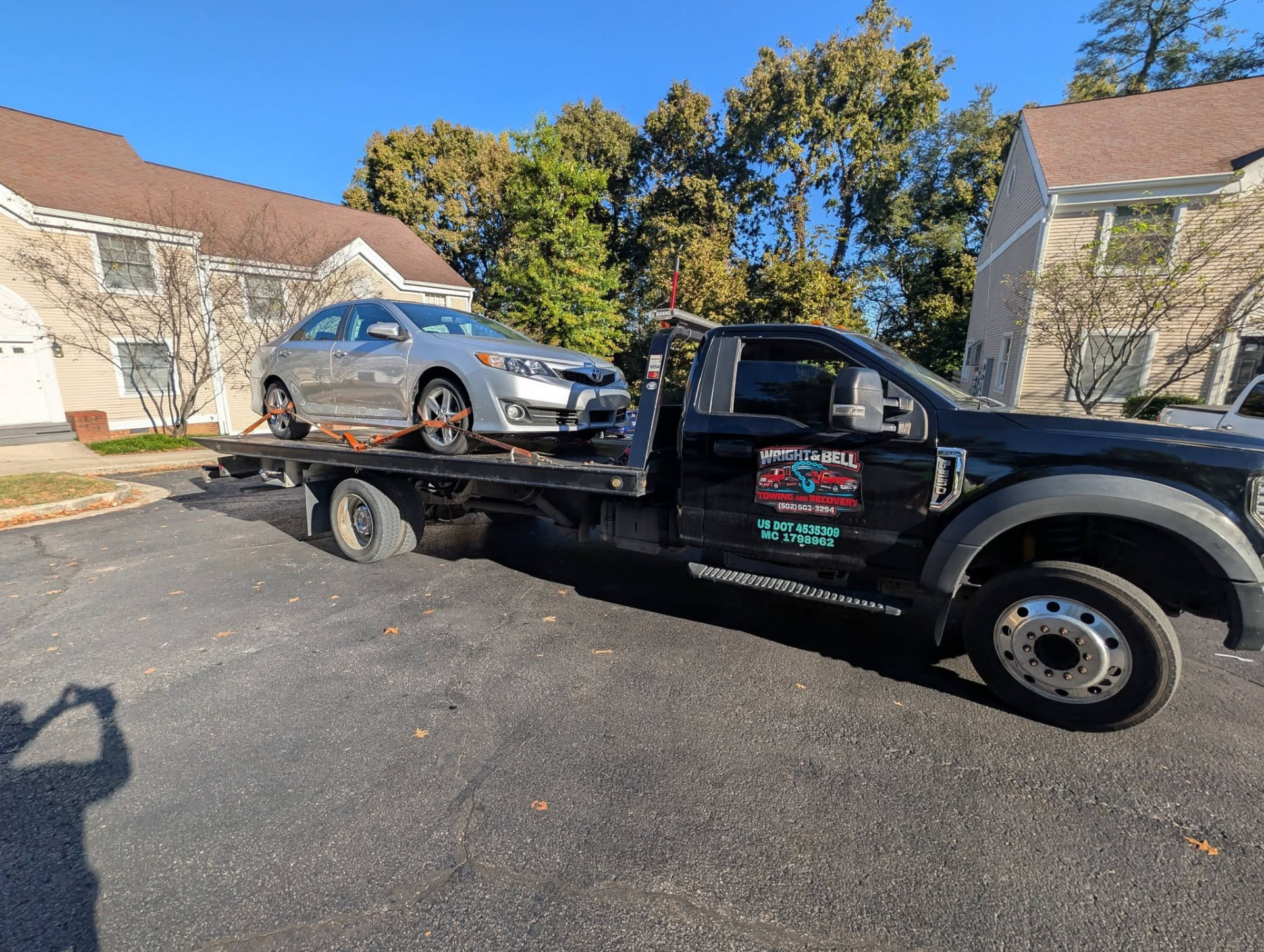 A silver car loaded on a flatbed in a Georgetown neighborhood