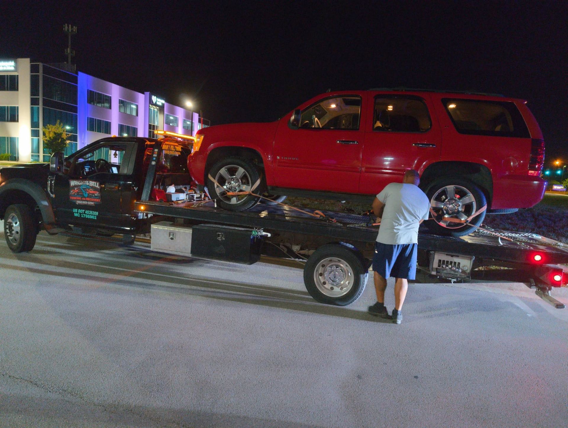 A red SUV being loaded onto the flatbed at night