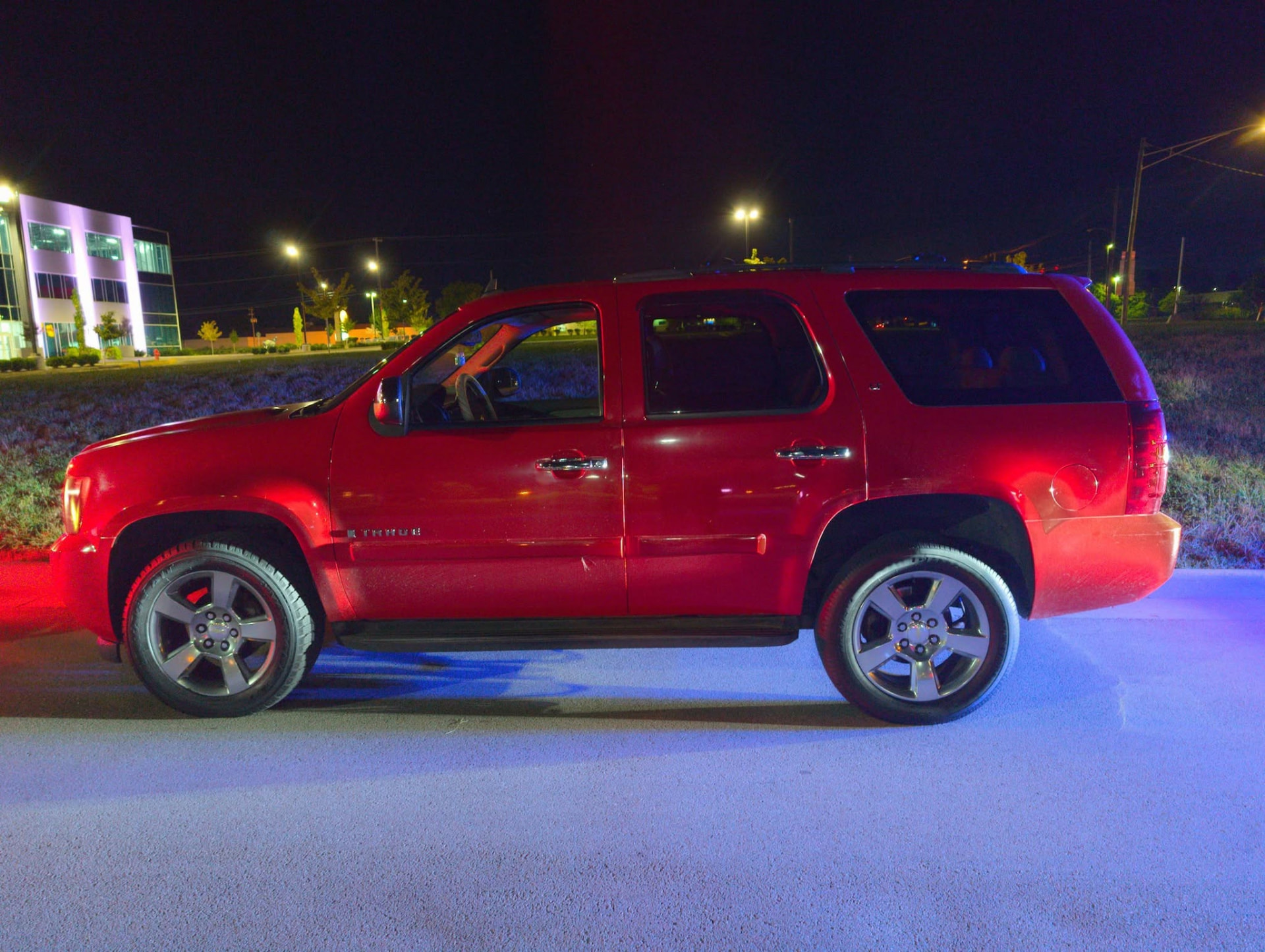 A red SUV loaded at night with the truck's lights glowing